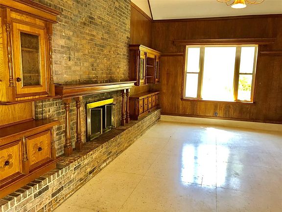 Dramatic sunken living room with fireplace, terrazzo flooring, built ins, and brick wall.