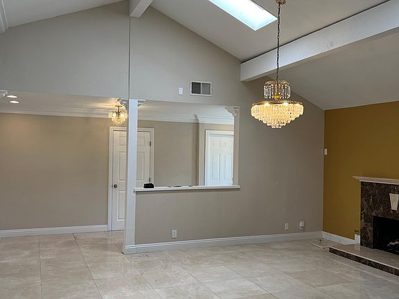Great room with cathedral ceiling, gas fireplace, marble flooring, custom chandelier, and skylight
