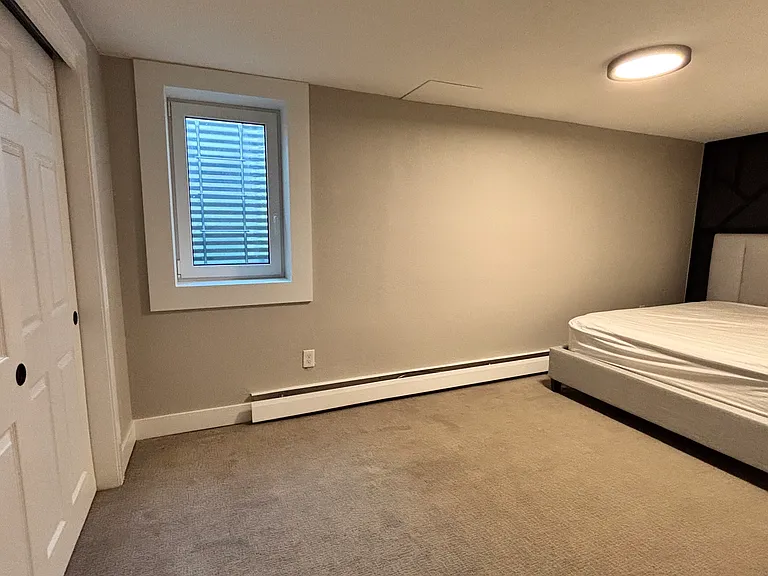 First bedroom. Well-lit area with wall-to-wall closet and modern decor.