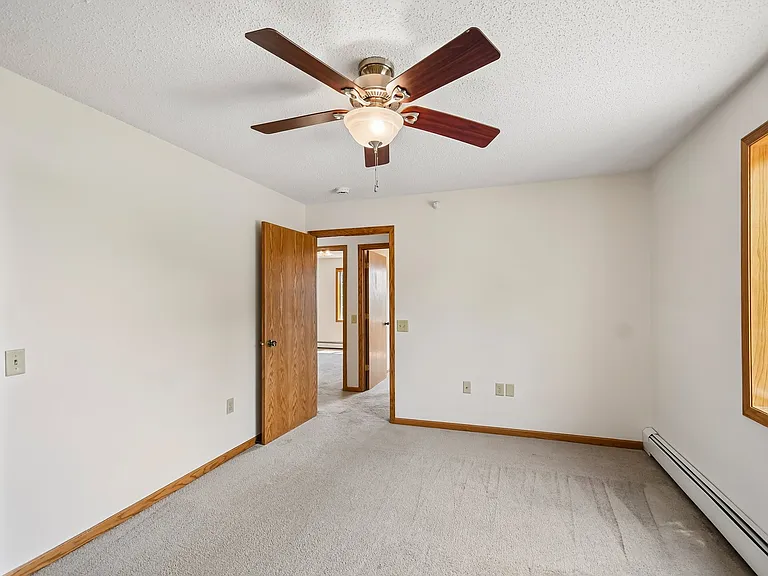 Embrace comfort and style at Mill Pond Apartments. This spacious bedroom features natural light, a ceiling fan for a refreshing breeze, and cozy carpeting, perfect for relaxation. Schedule a tour today and see it for yourself!