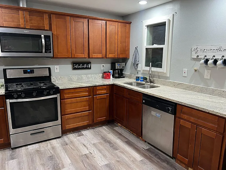 U-shaped kitchen with ample wood cabinetry, long counters, and stainless appliances including a gas range and dishwasher.