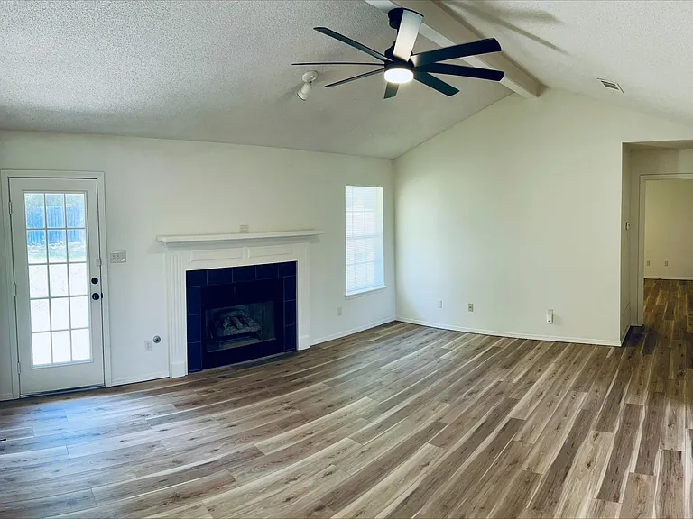Living room with vaulted ceiling and door to backyard and hallway to master bedroom and bathroom