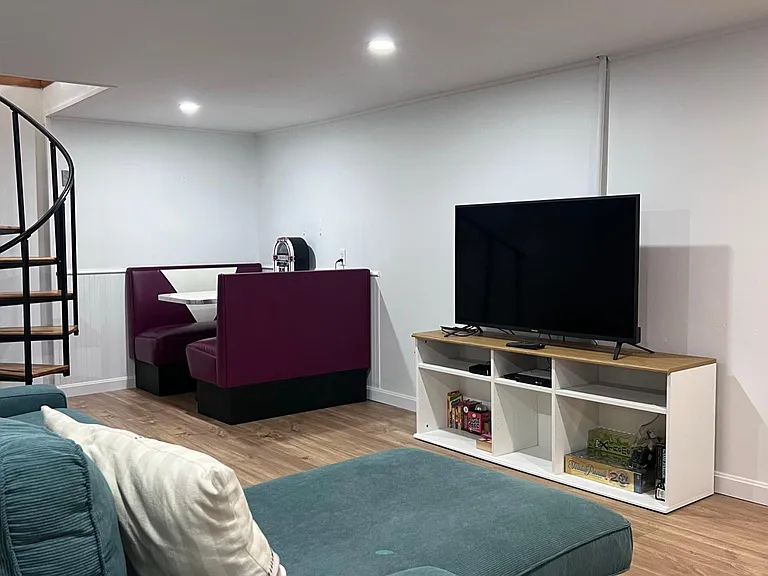 looking over the couch toward 50" flat screen, corner dinette, and spiral stair case