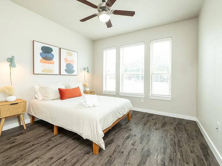 Cozy third bedroom with a queen bed, unique green hanging light fixtures on each side, and plenty of natural light_fresh, stylish, and serene. This bedroom is located upstairs.