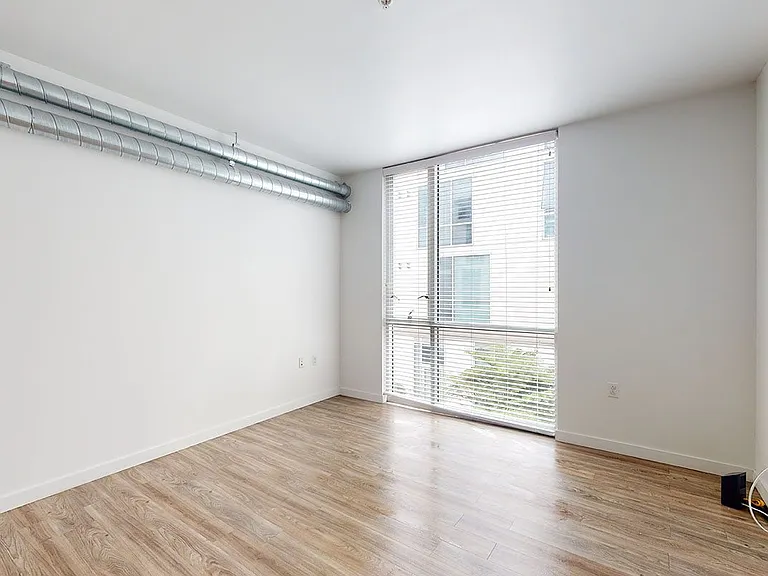 Apartment living room with wood-style flooring and floor-to-ceiling windows.