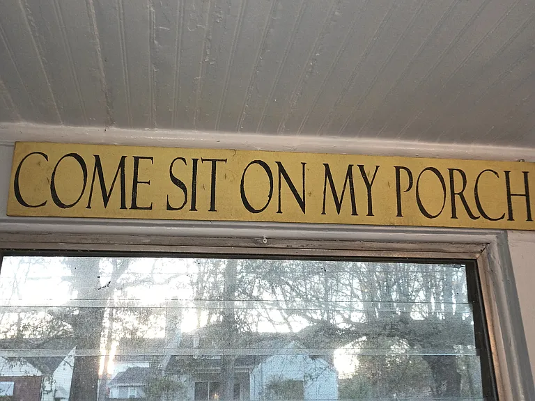 This photo is of a yellow wall hanging in the Sunroom on the property. It greets the Guest to "Come Sit on My Porch" There is nothing off color or obsene about it. 
 Please look at it an put it back.