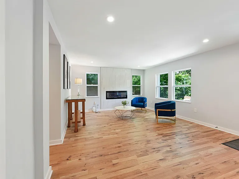 Spacious living room with wide-plank floors, large windows, and a sleek built-in fireplaceideal for relaxing or entertaining
