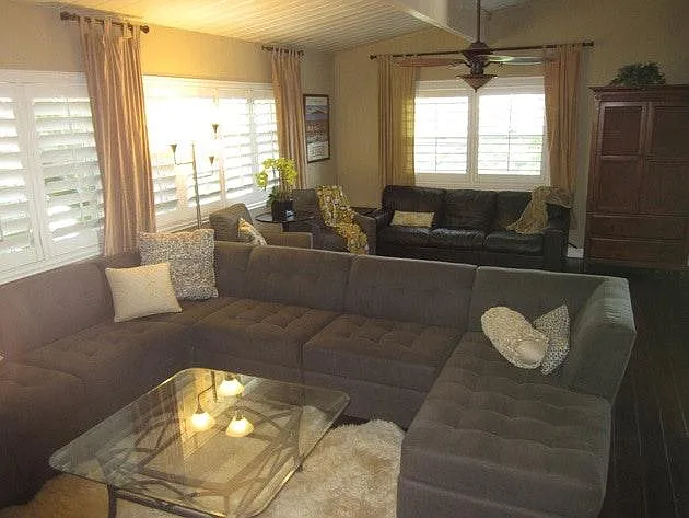 Large living room, wood floors, shutters, vaulted ceilings.