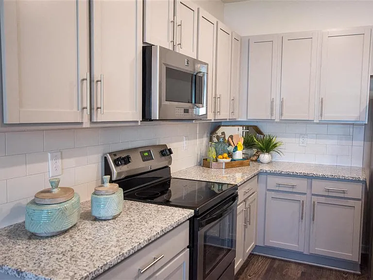 Kitchen with a stainless steel stove/oven and microwave. This kitchen has granite countertops and subway tile backsplash.