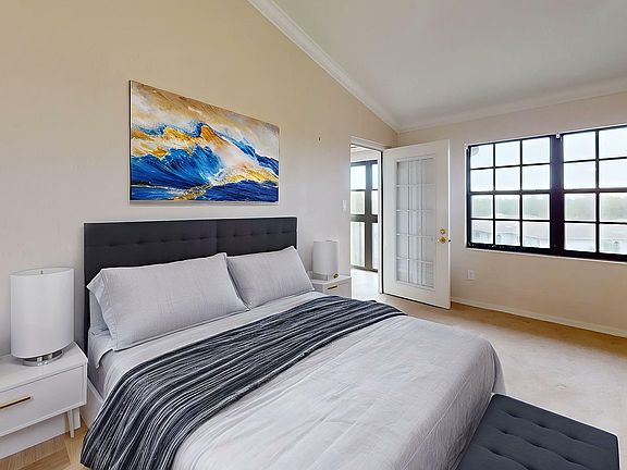 Elegant bedroom with modern decor, plush bed, and large windows offering abundant natural light.