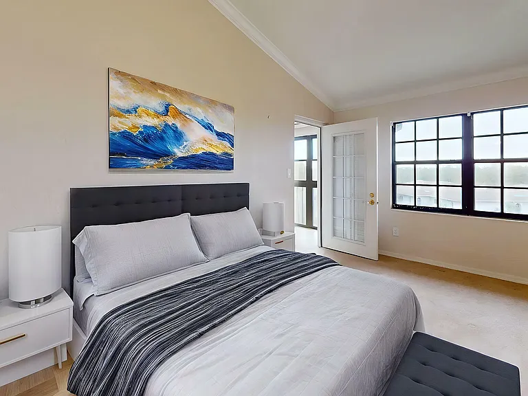 Elegant bedroom with modern decor, plush bed, and large windows offering abundant natural light.
