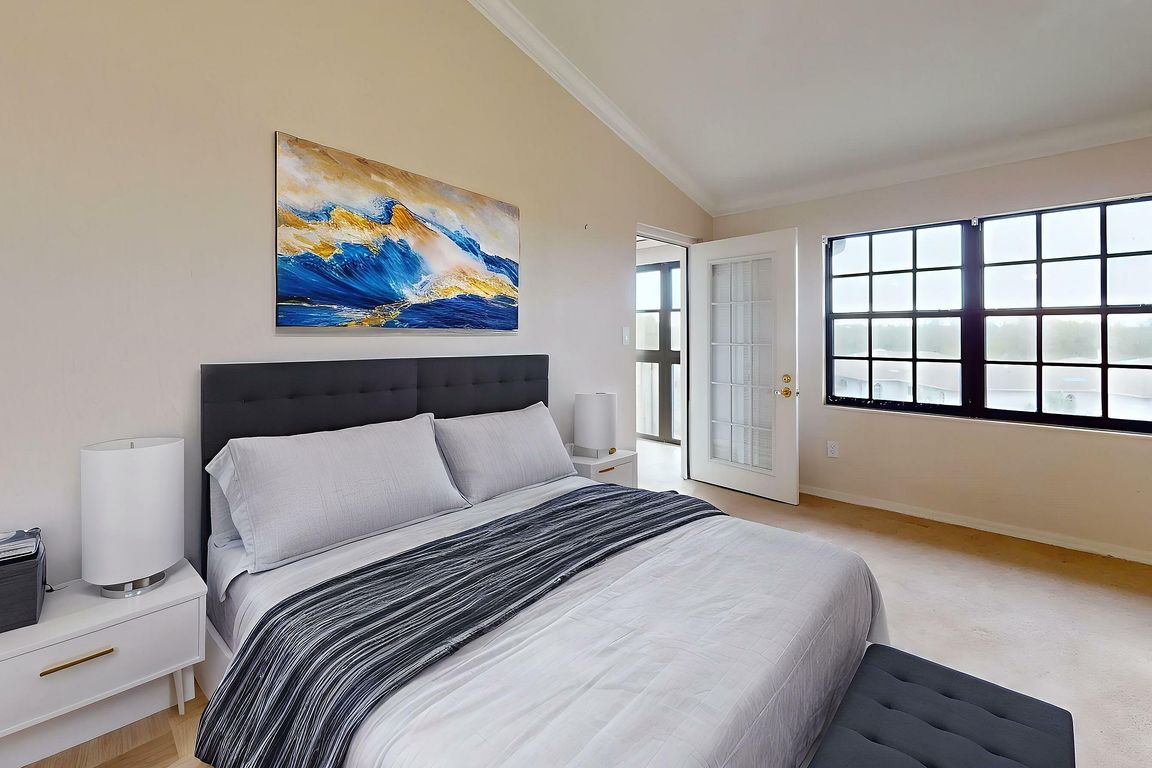 Elegant bedroom with modern decor, plush bed, and large windows offering abundant natural light.