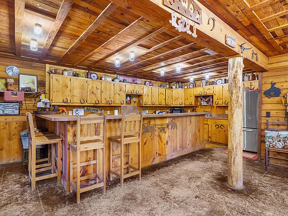 Kitchen with wooden walls, wood ceiling, freestanding refrigerator, and light countertops