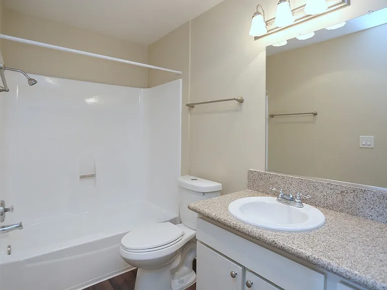 Bathroom with white fixtures and vanity with white cabinets in unit at Villa Pacific Apartments in Oceanside, California.