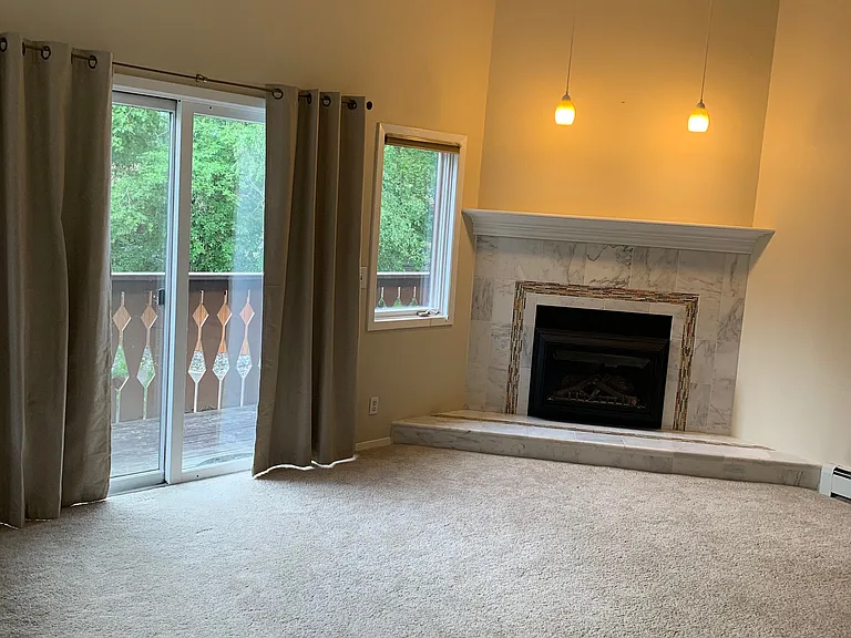 Fireplace in living room and sliding glass door to private deck