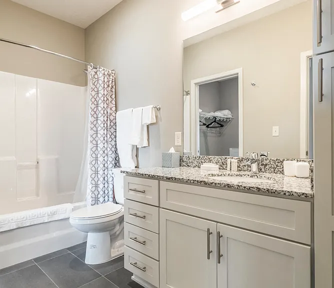 Bathrooms in our contemporary design scheme feature white cabinetry, light granite countertops and gray slate tile floors.