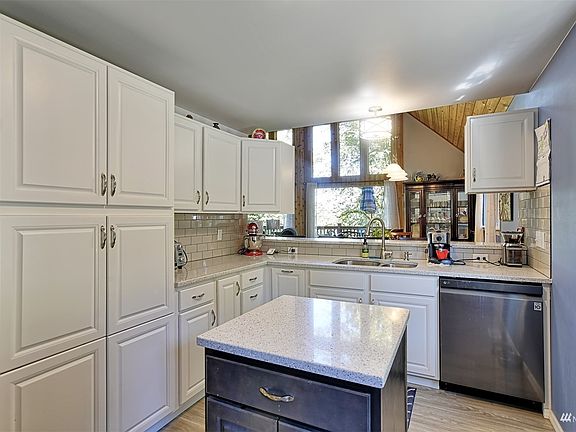 Beautiful quartz counter in the kitchen with lots of storage cabinets. Here it is shown from the eating bar and dining room area. Everything was brand new in 2018.>