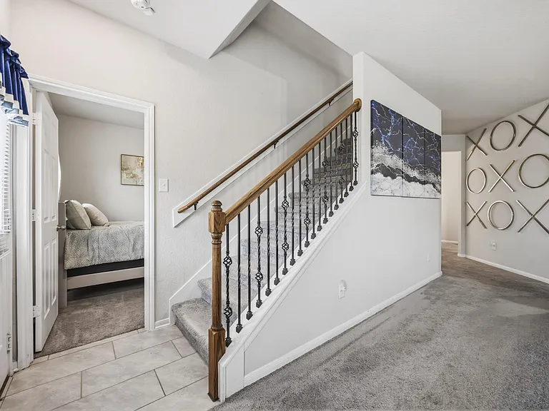 Open entry and stairway with carpeted steps, tiled foyer, and easy flow into nearby bedrooms and shared living areas.