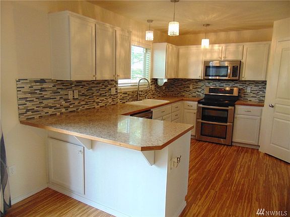 Kitchen has plenty of Cabinets, Pantry, Breakfast bar, custom lighting, tile backsplash . Stainless Steel Appliances ...