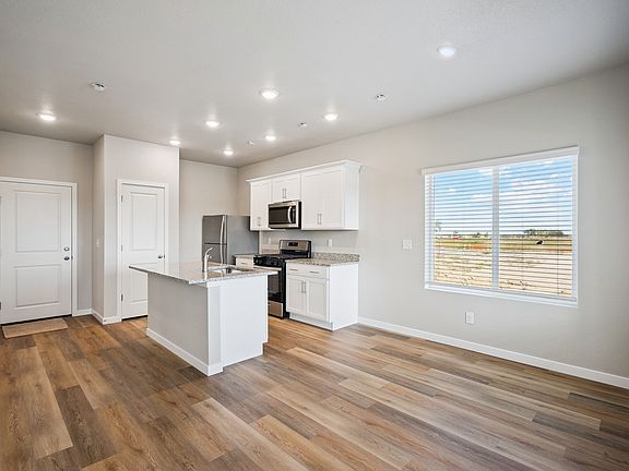 The kitchen has stainless steel appliances and plank flooring.