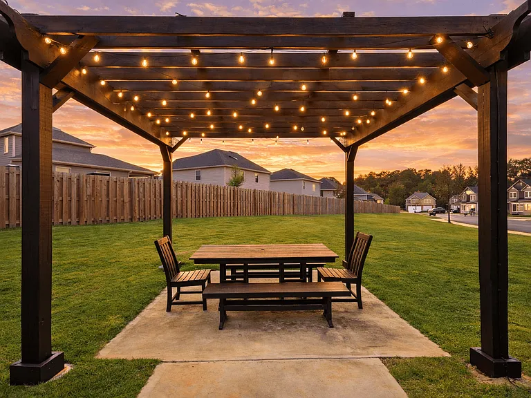 Backyard pergola with integrated lighting creates a warm, inviting outdoor setting.