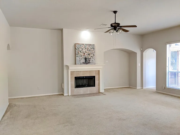 Spacious family room with high ceilings, fireplace, and large windows overlooking the backyard.