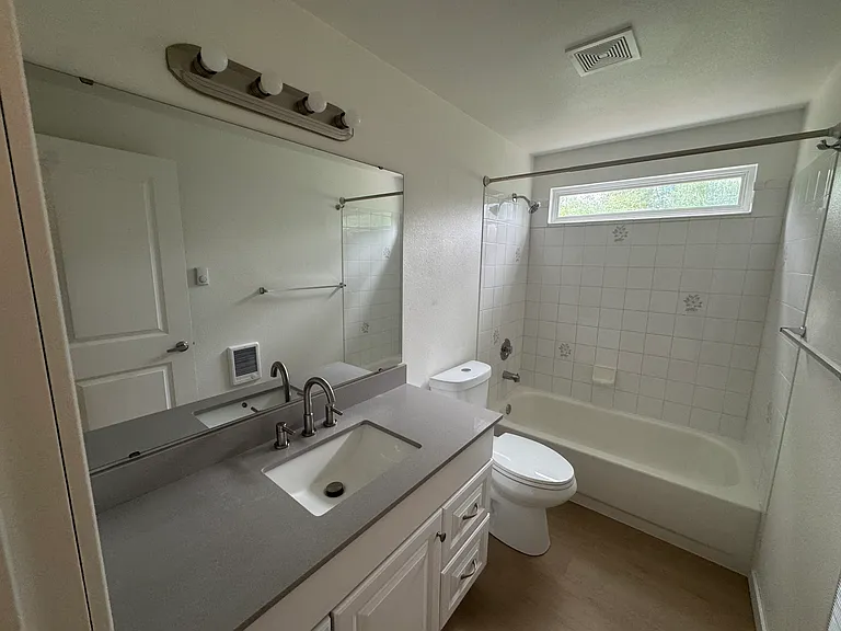 Private primary ensuite bathroom featuring a spacious vanity, tub/shower combination, and plenty of natural light.
