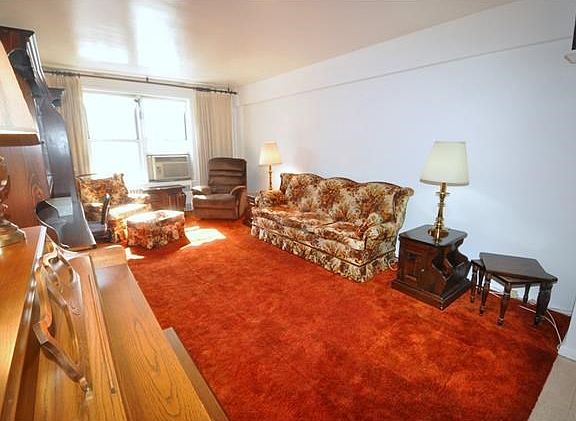 Large Sunny living room has covered hardwood floors and opens to the dining foyer.
