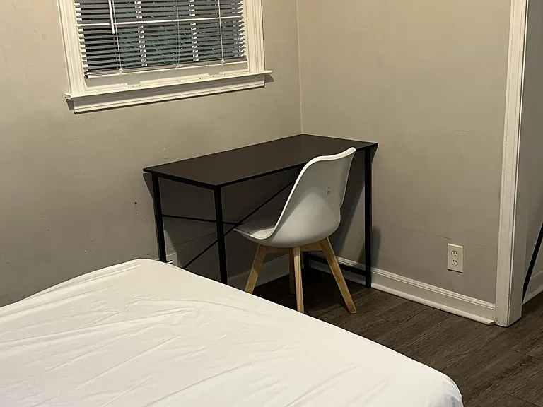 Bedroom work nook with a dedicated desk and chair near a window, offering a practical setup for studying or remote work.