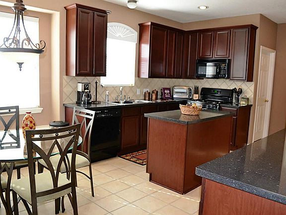 The kitchen features rich, warm tones from the granite counters and custom cabinets that compliment each other nicely! There is a convenient island, tile backsplash, recessed lights and a pendant light over the eat in breakfast area.