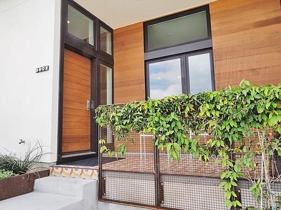 The crisp lines of the concrete steps leading to the front porch contrast with the fluid shapes and bright colors of the concrete tiles, while the siding tempers the modern feel with the warmth of natural wood.  The trumpet vine offers subtle privacy.