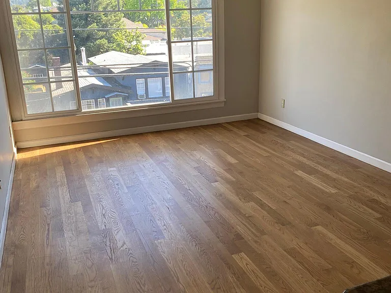 large living room area with hardwood floors, double pane picture windows views of Oakland hills.