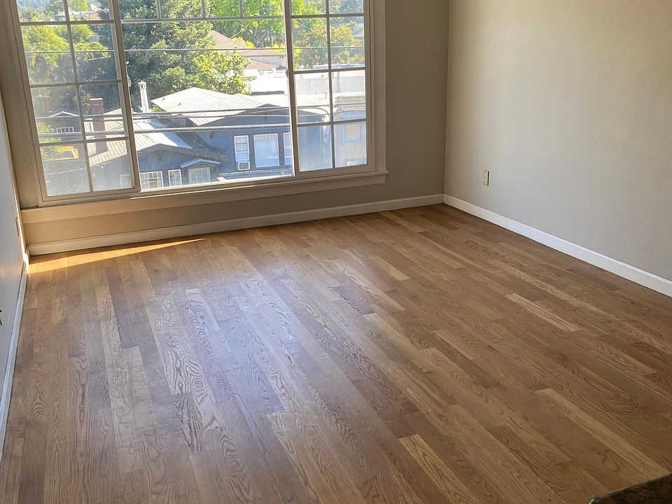 large living room area with hardwood floors, double pane picture windows views of Oakland hills.