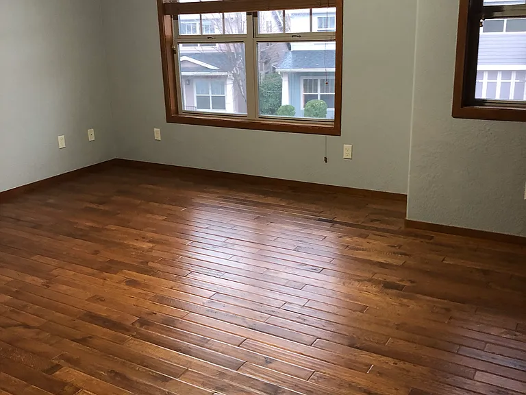Photo shows hardwood floors and view from the back