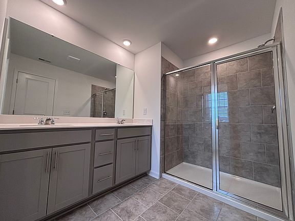 Spacious primary bathroom with ceramic tile and shower surround. Dual vanity.