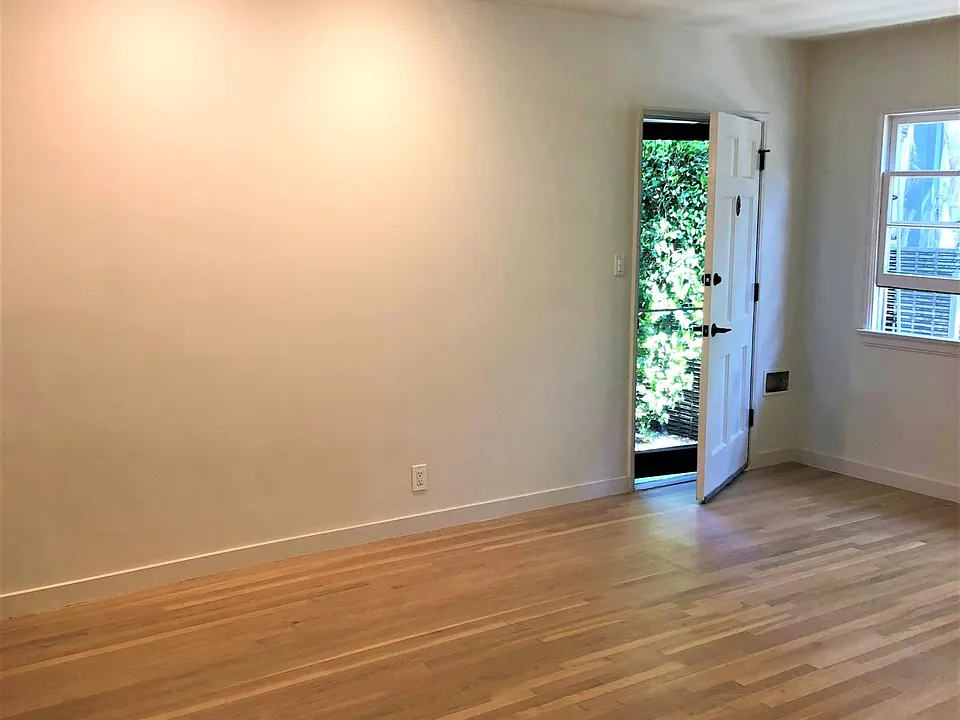 Front door and entry to living room with refinished hardwood floors and new recessed LED wall washers. 3 windows to the right.