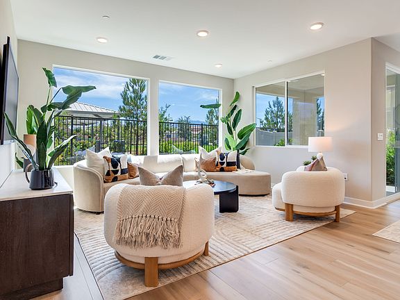 A cozy and inviting living room with large windows overlooking a lush outdoor landscape, featuring p