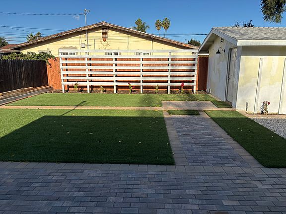 Backyard with multiple play areas and young Bougainvillea that will have red flowers when grown.