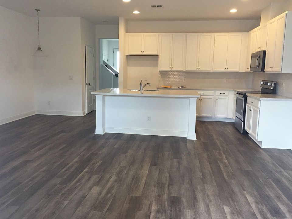 Open floor plan with kitchen, dining nook, pantry, island, chef kitchen (there is a stainless fridge) and large windows as well as a door to the backyard.