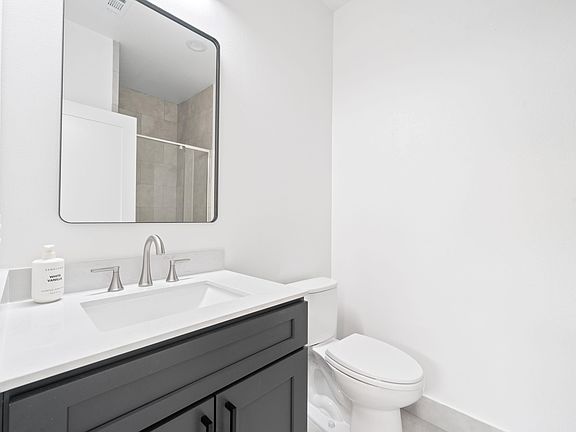 Bathroom with a sleek single-sink vanity, framed mirror, and shower/tub combo with tile surround.
