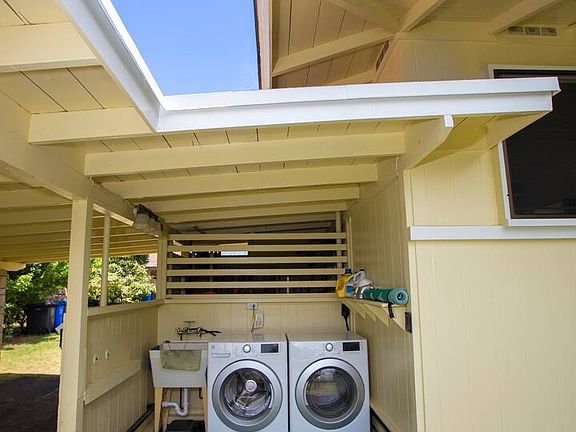 Outdoor laundry area with laundry sink and Kenmore front-loading washer and dryer.