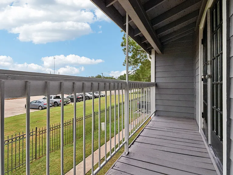 Charming balcony view with sleek metal railings, overlooking a vibrant green lawn under a clear blue sky. Charming balcony view with sleek metal railings, overlooking a vibrant green lawn under a clear blue sky.
