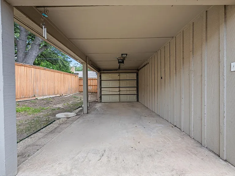 carport with garage door to fenced in back yard