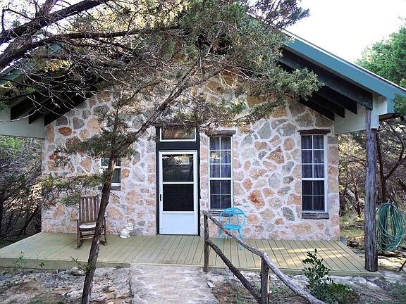 The front of the house is crafted of native stone, with an open front porch and native cedar beams, paved stone walk way with native cedar railing. There are no steps.