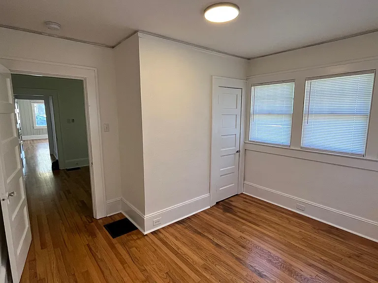 Third/back bedroom looking towards the middle bedroom adjacent door. Closet in this room is small and standard for a home built in the 1920s.