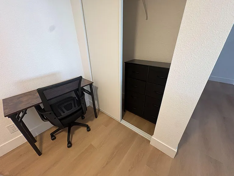 Dedicated nook with a work desk and chair plus a sliding-door closet featuring a multi-drawer dresser for storage.