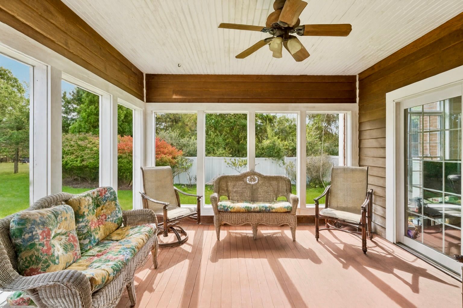Sunroom featuring a ceiling fan, mahogany wood walls, and a warm, inviting ambiance
