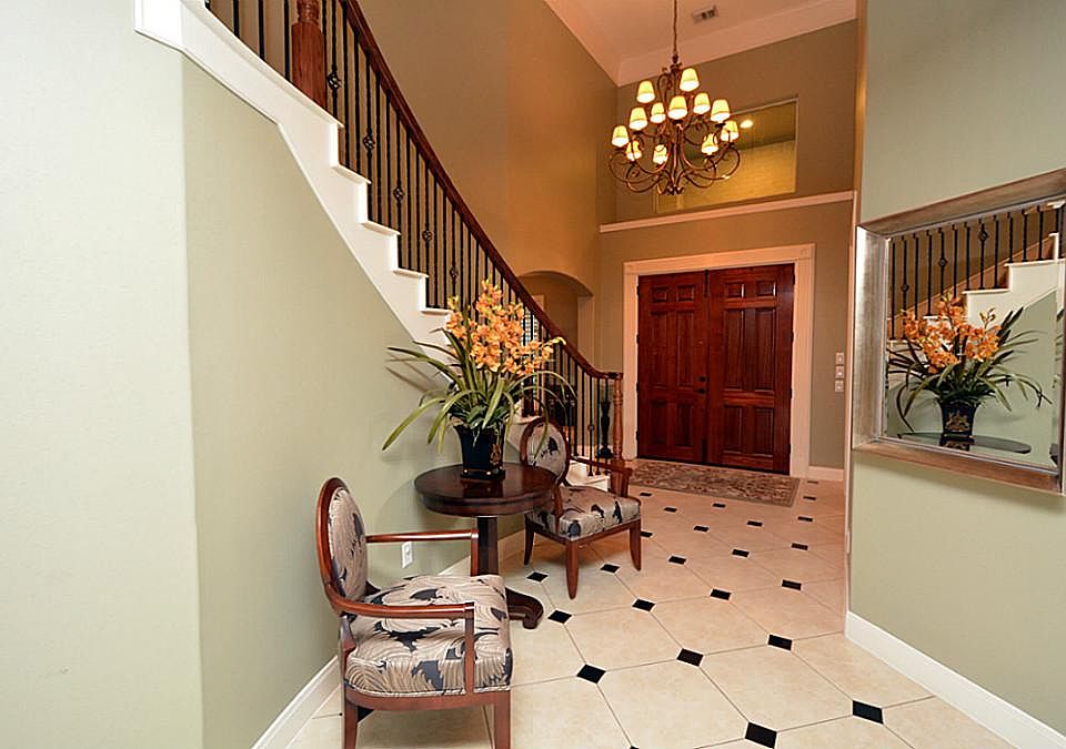 A view of the gorgeous foyer entry with soaring ceiling, granite inlaid tile and amazing chandelier.