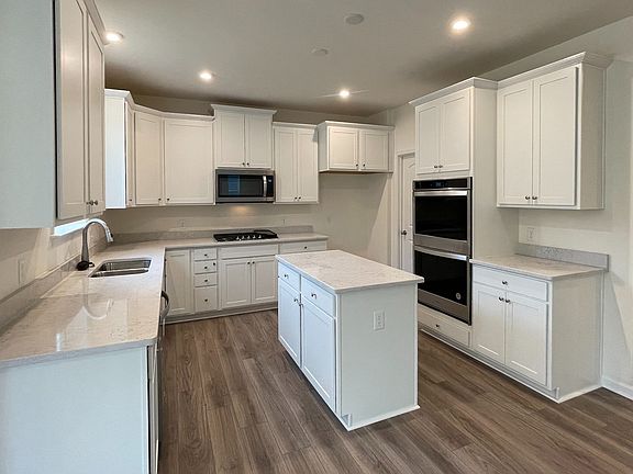 Island kitchen with white cabinets and counters in a DRB Homes Bristol II Plan at the Villas of Sout