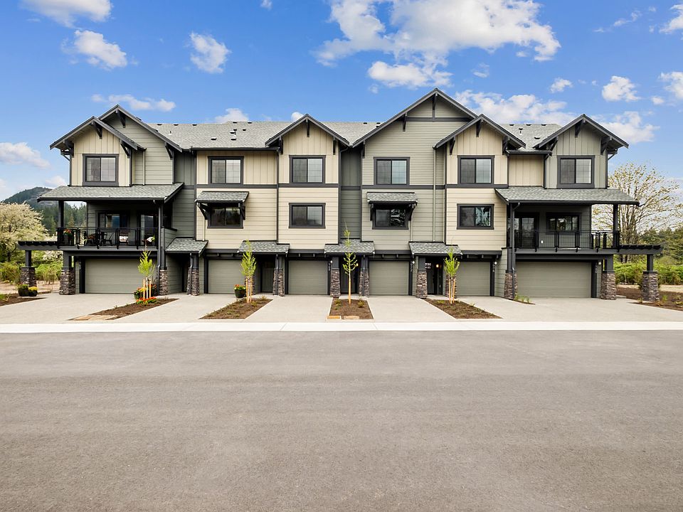A row of modern, multi-story townhouses with gabled roofs and attached garages, set against a backdr